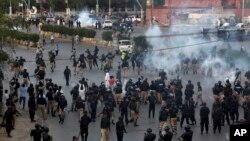 Pakistan police officers fire tear gas shell to disperse Shiite Muslims during an anti-U.S rally, when they tried to march toward the U.S. consulate, in Karachi, Pakistan, Aug. 27, 2017.