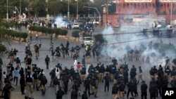 Pakistan police officers fire tear gas shell to disperse Shi'ite Muslims during an anti-U.S rally, when they tried to march toward the U.S. consulate, in Karachi, Pakistan, Aug. 27, 2017.