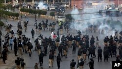 Pakistan police officers fire tear gas shell to disperse Shi'ite Muslims during an anti-U.S rally, when they tried to march toward the U.S. consulate, in Karachi, Pakistan, Aug. 27, 2017.