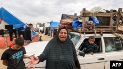 FILE - A woman reacts as she stands before a vehicle loaded with items secured by rope as people flee from Rafah in the southern Gaza Strip on February 13, 2024 north towards the center of the Palestinian territory.