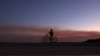 A bicyclist takes a photo as smoke from the Palisades Fire rises in the distance in the community of Topanga, California, on January 9, 2025.