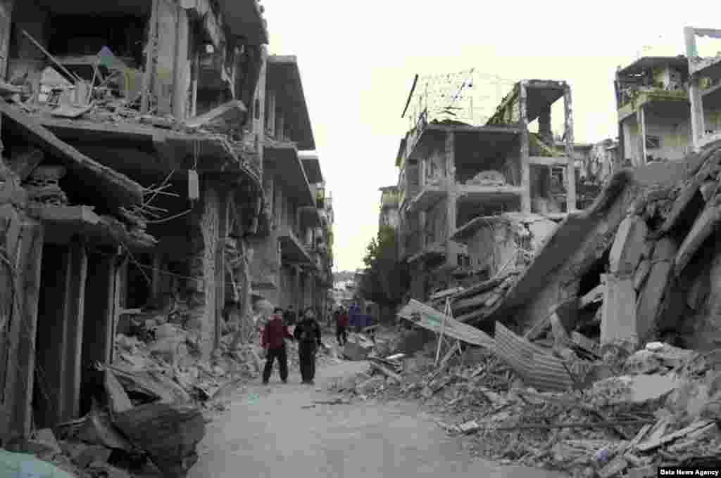 2012年11月29日，在叙利亚霍姆斯省，叙利亚人走在一条被叙利亚战机炸坏的街道上。
