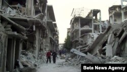 Syrian citizens walk in a destroyed street that was attacked on Wednesday by Syrian forces warplanes, at Abu al-Hol street in Homs province, Syria, Nov. 29, 2012.