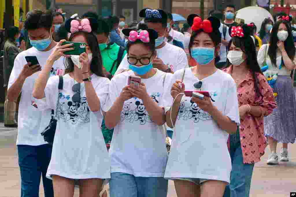 Visitors, wearing face masks, enter the Disneyland theme park in Shanghai, China.