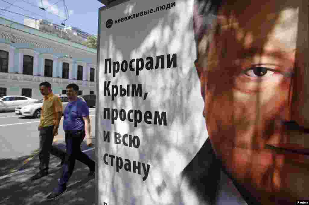 People walk past a billboard in Moscow with an image of Ukrainian President Petro Poroshenko. The text reads&nbsp;&quot;Impolite people. We screwed up in Crimea, we will screw up in the whole country too,&quot; June 30, 2014.