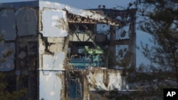 The crippled Fukushima Daiichi nuclear power plant's No.4 reactor building is seen through bus windows in Fukushima prefecture, November 12, 2011.