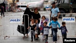 A Syrian family walks past a blast site in the town of Reyhanli of Hatay province near the Turkish-Syrian border, May 12, 2013.