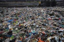 A man walks on the shores the Arabian Sea, littered with plastic and other garbage in Mumbai, India, Monday, June 4, 2018. The theme for this year's World Environment Day, marked on June 5, is "Beat Plastic Pollution." (AP Photo/Rafiq Maqbool)