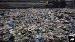 A man walks on the shores the Arabian Sea, littered with plastic and other garbage in Mumbai, India, Monday, June 4, 2018. The theme for this year's World Environment Day, marked on June 5, is "Beat Plastic Pollution." (AP Photo/Rafiq Maqbool)