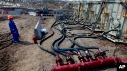 FILE - A worker helps monitor water pumping pressure and temperature at a hydraulic fracturing and extraction site outside Rifle, in western Colorado. The Trump administration has rescinded proposed federal rules covering fracking.