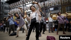 Elderly and middle-age people exercise during a health promotion event in Tokyo, September 2015. (REUTERS/Issei Kato)