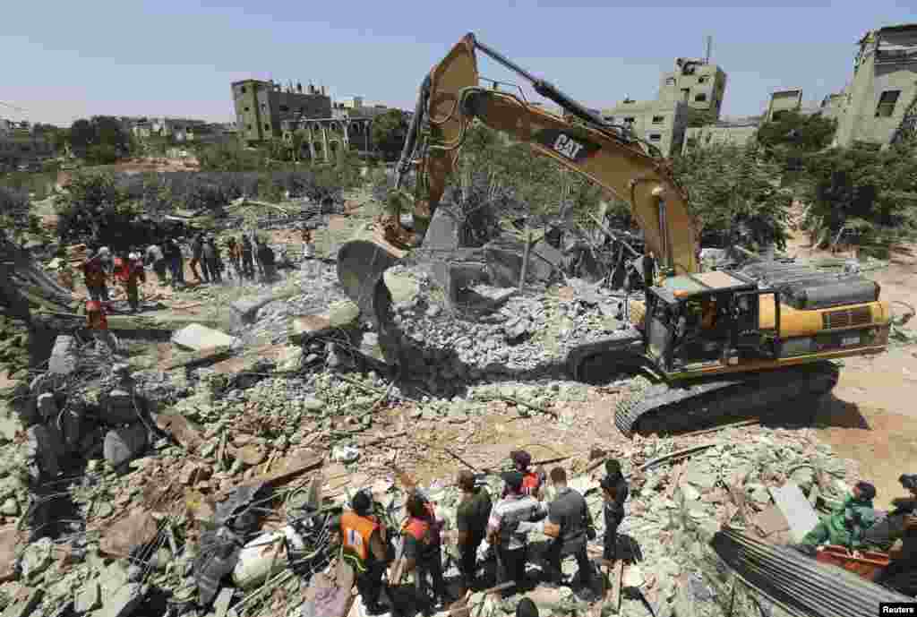 Palestinians gather as  rescue workers search for victims from under the rubble of a house, which witnesses said was destroyed by an Israeli air strike, in Beit Lahiya in the northern Gaza Strip August 25, 2014. Israel's Prime Minister Benjamin Netanyahu 