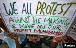 Seorang pria menunjukkan poster yang berisi pernyataan menentang pembuatan film anti-Islam di Jammu, India, 21 September 2012.