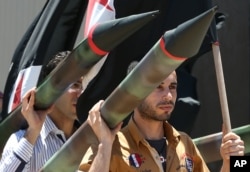 Two Lebanese men carry a fake missile to protest against the Israeli offensive in Gaza, as they take part in a sit-in, in front the United Nations headquarters, in downtown Beirut, Lebanon, July 13, 2014.