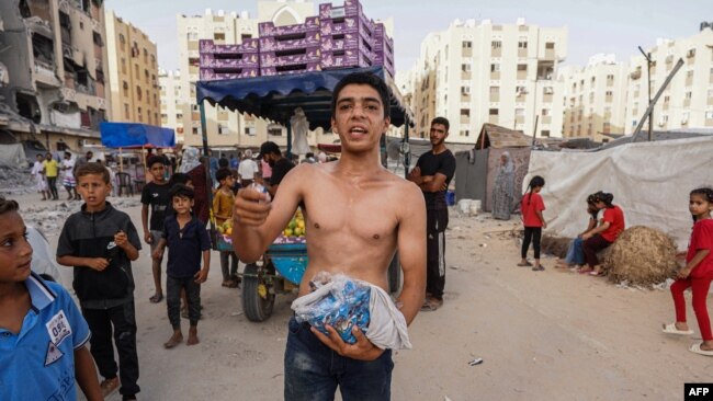 Palestinians collect food items from airdropped aid parcels in the Hamad City area in Khan Yunis in the southern Gaza Strip on July 4, 2024.