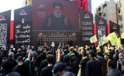 FILE - Lebanon's Hezbollah leader Sayyed Hassan Nasrallah addresses his supporters via a screen during the religious procession to mark the Shiite Ashura ceremony, in Beirut, Sept. 10, 2019.
