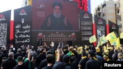 FILE - Lebanon's Hezbollah leader Sayyed Hassan Nasrallah gestures as he addresses his supporters via a screen during the religious procession to mark the Shi'ite Ashura ceremony, in Beirut, Lebanon, Sept. 10, 2019.