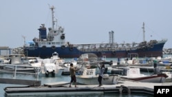 Les pêcheurs vérifient leur filet devant les navires amarrés dans le port de Fujairah le 2 juillet 2019 à l'est des Émirats arabes unis (EAU).