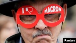 A demonstrator wears cardboard glasses with the message, "I don't like Macron", in refererence to French president-elect Emmanuel Macron, as people gather to protest the day after the country went to the polls, in Paris, May 8, 2017. 