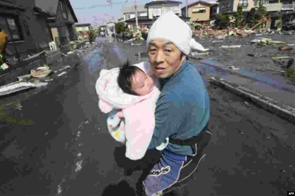 Upon hearing another tsunami warning, a father tries to flee for safety with his just reunited four-month-old baby girl who was spotted by Japan's Self-Defense Force member in the rubble of tsunami-torn Ishinomaki Monday, March 14, 2011, three days after 