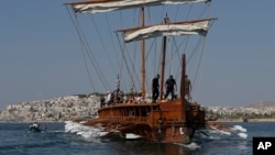 FILE - Visitors row the Olympias, a replica of an ancient galley, at Saronic gulf in southern Athens. 