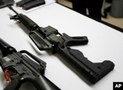 In this Jan. 11, 2018 photo, a semi-automatic rifle at right that has been fitted with a so-called bump stock device to make it fire faster sits on a table at the Washington State Patrol crime laboratory in Seattle.