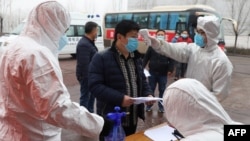 山东省邹平在公交车站设立检查点为来自河南的农民工测量体温。（2020年2月25日）