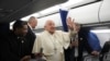 El papa Francisco saluda a los periodistas en el vuelo de regreso a Roma al final de su visita de un día a Ajaccio en la isla francesa de Córcega, el 15 de diciembre de 2024.