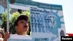 A woman holds a replica green card sign during a protest march to demand immigration reform in Hollywood, Los Angeles, California, October 5, 2013. REUTERS/Lucy Nicholson (UNITED STATES - Tags: POLITICS CIVIL UNREST TPX IMAGES OF THE DAY) - RTR3FMYJ