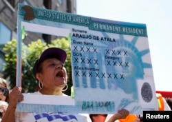FILE - A woman holds a replica green card sign during a protest march to demand immigration reform in Hollywood, Los Angeles, California, October 5, 2013. (REUTERS/Lucy Nicholson)