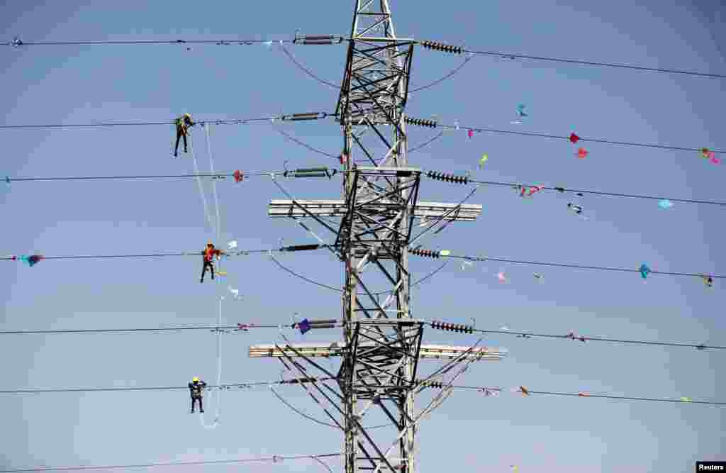 Workers of Torrent Power Limited remove kites and thread attached to electric power cables after the end of the kite-flying season in Ahmedabad, India.