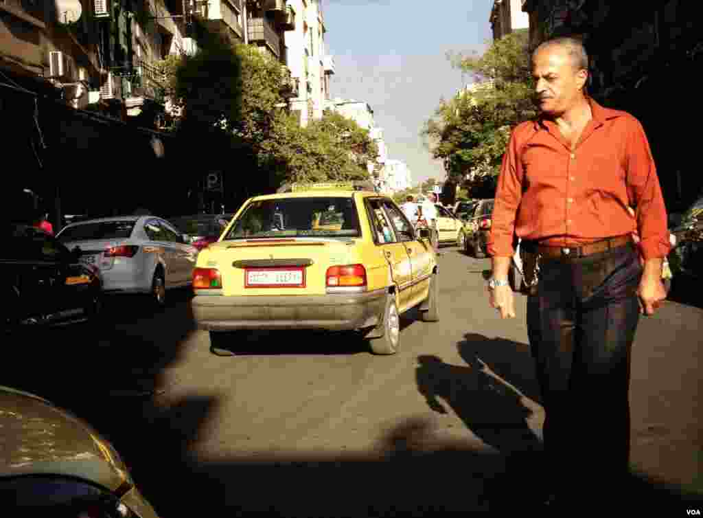 一名男子在大马士革一条繁忙的街道上穿行。虽然有些街道因为安全原因而关闭，但多数道路仍然通车。(J. Weeks/VOA)