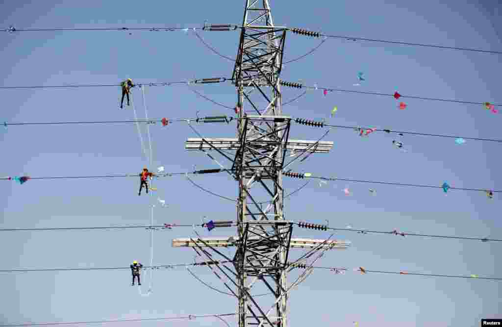 Workers of Torrent Power Limited remove kites and thread tangled up in electric power cables after the end of the kite-flying season in Ahmedabad, India.