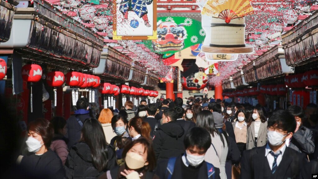 People wearing face masks to protect against the spread of the coronavirus walk under decorations for new year through the alley leading to Asakusa Sensoji Buddhist temple in Tokyo, Dec. 21, 2021. (AP Photo/Koji Sasahara)