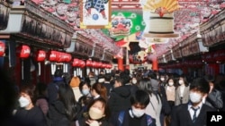 People wearing face masks to protect against the spread of the coronavirus walk under decorations for new year through the alley leading to Asakusa Sensoji Buddhist temple in Tokyo, Dec. 21, 2021. (AP Photo/Koji Sasahara)