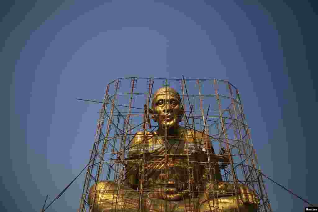 Workers climb scaffolding as they put the final touches to a large religious statue at the Buddhist temple near Amphawa floating market at Samut Songkhram province, Thailand.