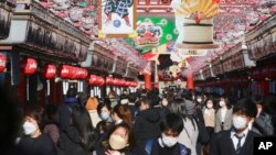 People wearing face masks to protect against the spread of the coronavirus walk under decorations for new year through the alley leading to Asakusa Sensoji Buddhist temple in Tokyo, Dec. 21, 2021. 