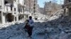 FILE - A Syrian man holds a girl as he stands on the rubble of houses that were destroyed by Syrian government forces air strikes in Aleppo, Syria, April 21, 2014.