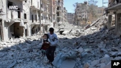 FILE - A Syrian man holds a girl as he stands on the rubble of houses that were destroyed by Syrian government forces air strikes in Aleppo, Syria, April 21, 2014.