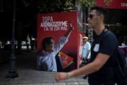 People walk past a poster depicting Greek PM Tsipras at the election kiosk of the leftist Syriza party in Athens.