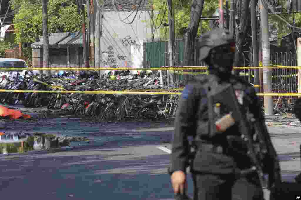 Seorang petugas kepolisian berjaga dekat lokasi terjadinya ledakan di luar sebuah gereja di Surabaya, Jawa Timur, Minggu, 13 Mei 2018.&nbsp; Pelaku menyasar gereja-gereja di kota terbesar kedua di Indonesia, Surabaya, Minggu pagi.