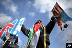 A Palestinian protester burns mock American and British flags as thousands of employees of the U.N agency for Palestinian refugees demonstrate in support of their organization following U.S. funding cuts in Gaza City, Jan. 29, 2018.