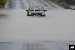 Sebuah mobil terdampar di jalan yang banjir akibat badai di Windsor, California, Kamis, 21 November 202. (Godofredo A.Vásquez/AP)