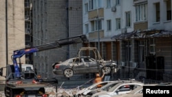 Сотрудники киевских городских служб транспортируют со стоянки автомобили, поврежденные во время российского обстрела. 30 мая 2023 г. 