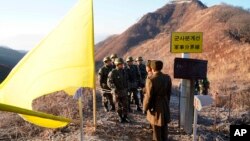 FILE - In this photo provided by South Korea Defense Ministry, South Korean army soldiers, wearing helmets, prepare to cross the Military Demarcation Line as North Korean army soldiers stand inside the Demilitarized Zone in Cheorwon, on Dec. 12, 2018. 