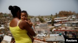 Ysamar Figueroa, y su hijo Saniel, observan el daño causado por el huracán María a su barrio en Canovanas, Puerto Rico. Sept. 26, 2017.