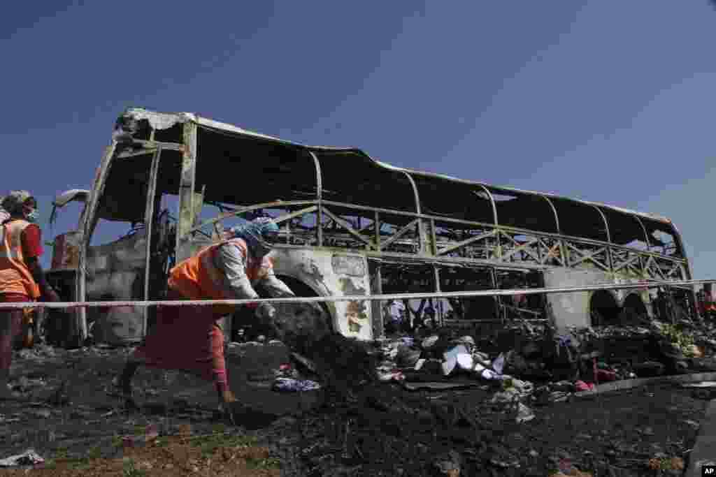 Workers clean debris after a bus crashed into a highway barrier and erupted in flames, Mehabubnagar, Andhra Pradesh, India, Oct. 30, 2013. 