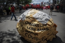 Tulisan "omnibus law lebih berbahaya dari COVID" tampak di tengah demo buruh memprotes Undang-Undang Cipta Kerja, di Bandung, Jawa Barat, Selasa, 6 Oktober 2020. (Foto: Antara via Reuters)