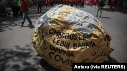 Tulisan "omnibus law lebih berbahaya dari COVID" tampak di tengah demo buruh memprotes Undang-Undang Cipta Kerja, di Bandung, Jawa Barat, Selasa, 6 Oktober 2020. (Foto: Antara via Reuters)