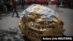 Tulisan "omnibus law lebih bahaya dari COVID" tampak di tengah demo buruh memprotes Undang-Undang Cipta Kerja, di Bandung, Jawa Barat, Selasa, 6 Oktober 2020. (Foto: Antara via Reuters)